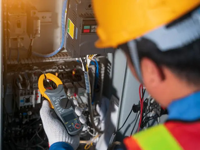 Mann mit Helm misst Spannung